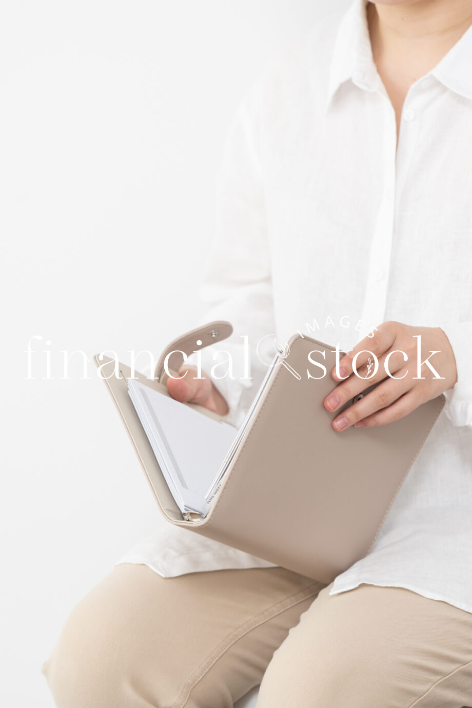Financial Stock Images - Woman working from home holding a beige diary.